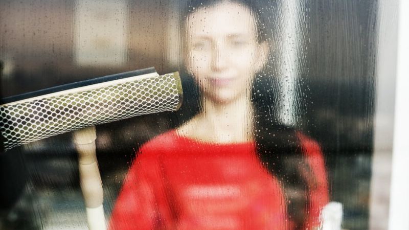 Женщина моет запотевшее окно