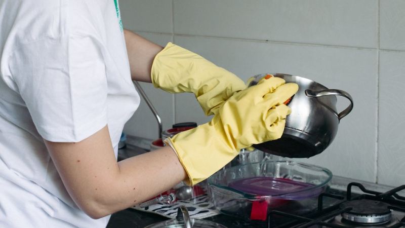 Женщина отмывает кастрюлю от пригоревшего варенья: