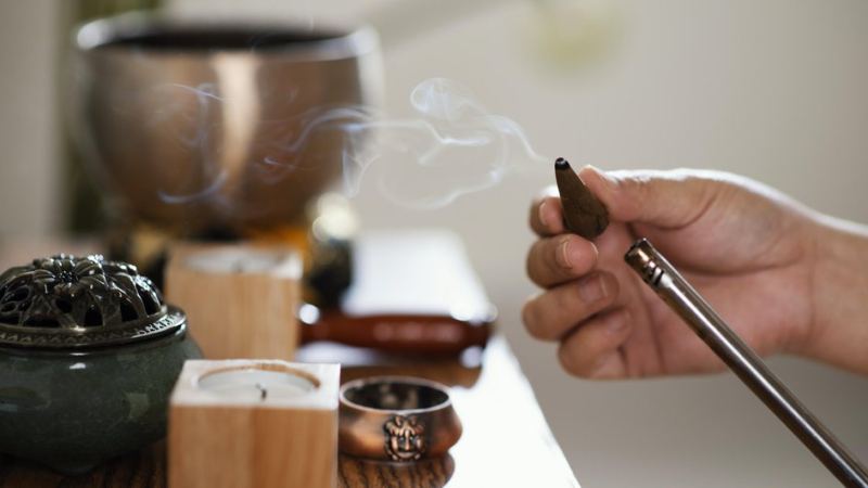 Человек с помощью благовоний проводит сентябрьские ритуалы для дома